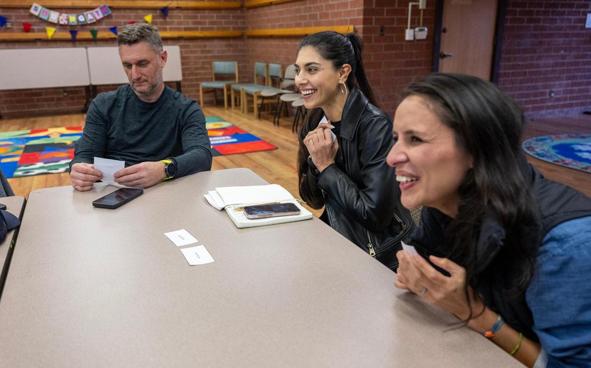 Laura Garcia Mera, right, and Veronika Morel, center, react during the word game “Go Fish” at the Southgate Library earlier this month. 
