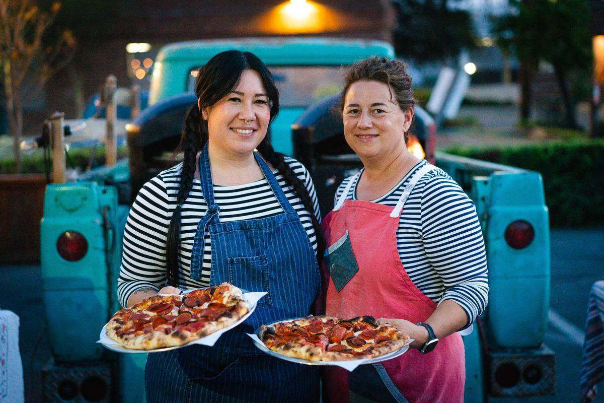 Jodie Chavious (R) left fine dining behind to make pizzas out of the back of an old Ford truck, sometimes assisted by Jane Anderson (L).