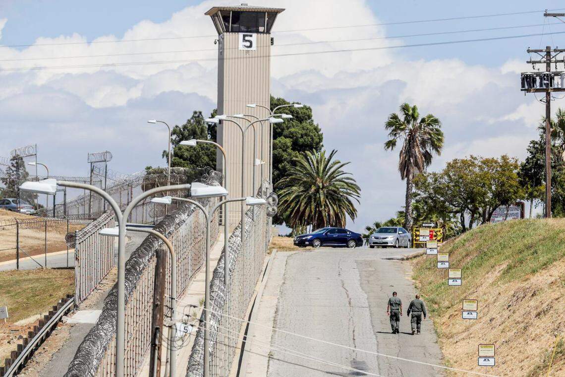 Guards walk along the south side of the California Rehabilitation Center in Norco in 2019. 