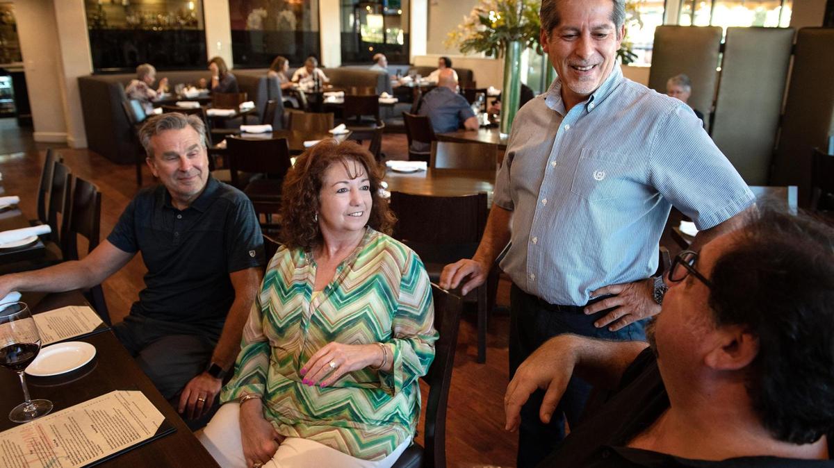 El propietario Jaime Alderete, de pie, habla con los clientes Greg y Carla Ciccarelli, a la derecha y en el centro, y Paul La Flamme, a la izquierda, en Verona's Cucina Italiana en Modesto, el miércoles 1º de septiembre de 2021.