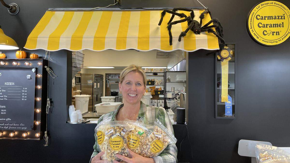 Founder Karen Carmazzi of Carmazzi Caramel Corn at 520 La Sierra Drive, Sacramento, holds bags of her popcorn on Monday, Oct. 23, 2023. Service journalism reporter Brianna Taylor visited the family-owned business on a $25 budget as part of The Sacramento Bee’s affordability series.