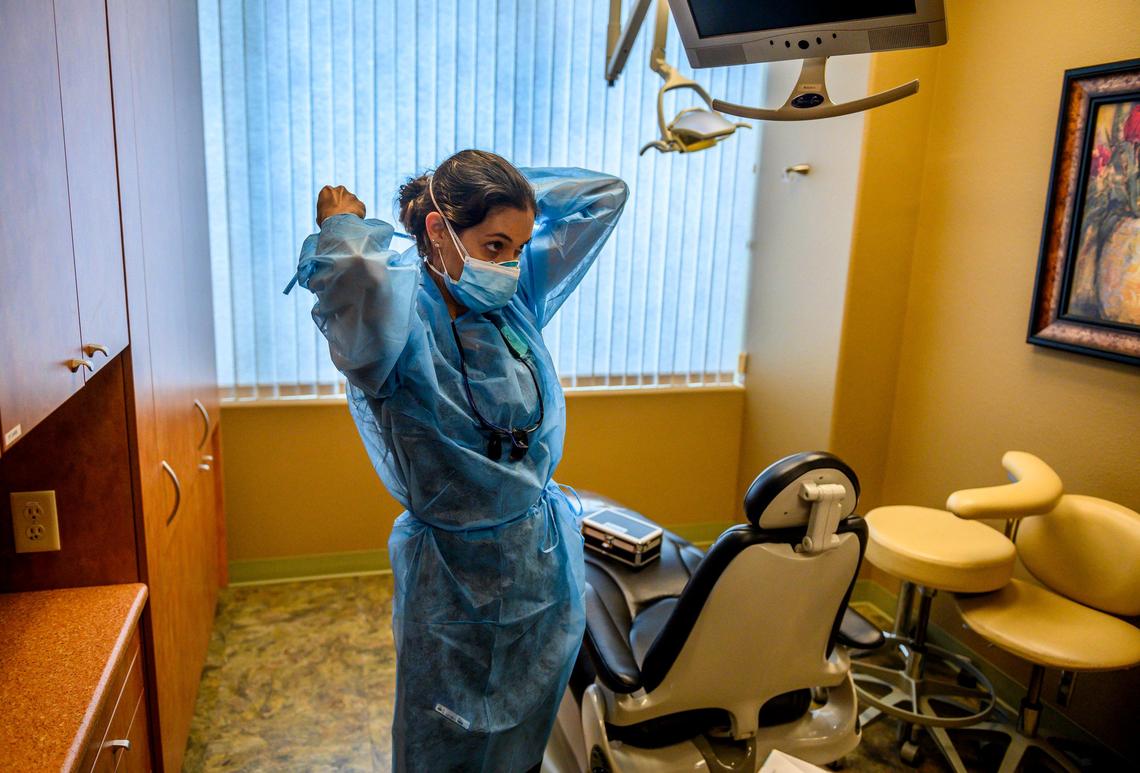 Dentist Stephanie Sandretti, owner of Galleria Smile Designs, demonstrates how she will see her patients by putting on her personal protective equipment at her practice in Roseville on Tuesday, May 12, 2020. After nearly two months of closed offices and emergency-only dental work due to the coronavirus pandemic, California dentists are reopening offices this week. “We are going to have new protocols in terms of how patients are going to be checked in. They are going to be having their temperature taken, washing their hands, wearing masks in the office. Us dentists and staff will be wearing a lot more PPE,” she said.