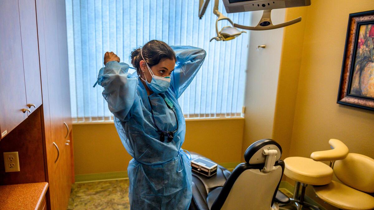 Dentist Stephanie Sandretti demonstrates how she will see her patients by putting on her personal protective equipment at her practice in Roseville on Tuesday, May 12, 2020.