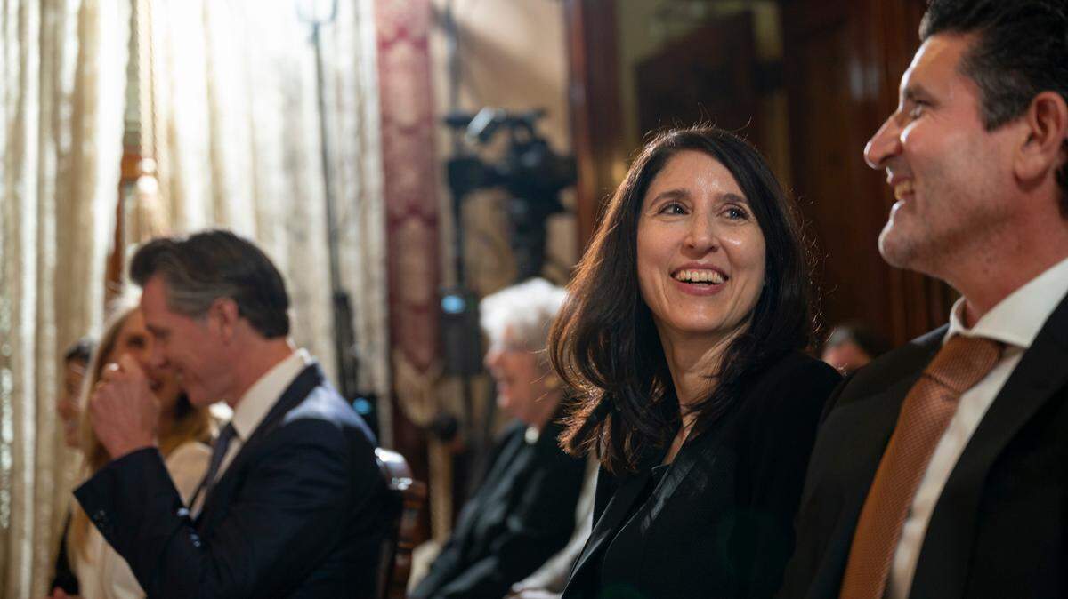 Patricia Guerrero, center, shares a laugh with husband Joe Dyson, right, before being sworn in to the California Supreme Court on Monday, March 28 by Gov. Gavin Newsom, background left, at the Stanford Mansion in Sacramento.
