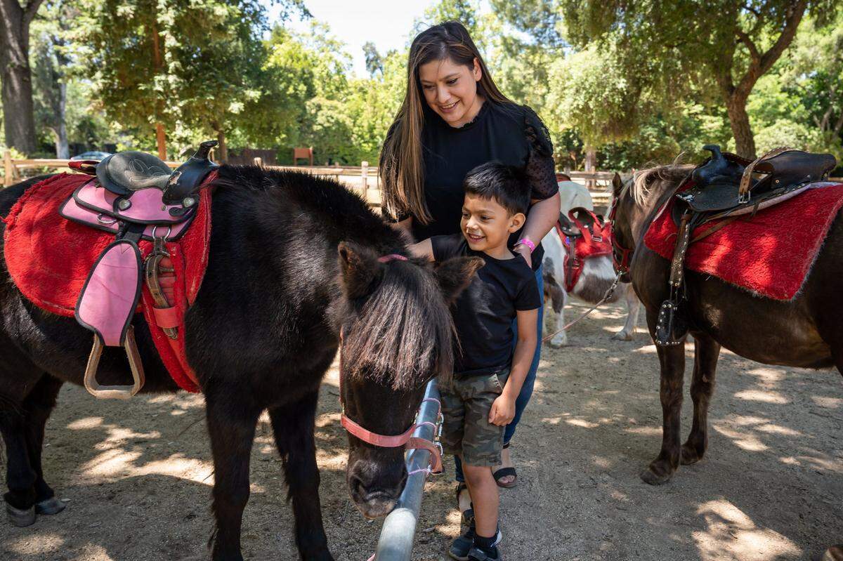 Julian Marroquin, 4, of Galt, pets Black Beauty after riding Hotshot, with help from his mother, Letisia Marroquin, on the last day of operations for Land Park Pony Rides on Monday at Land Park in Sacramento.