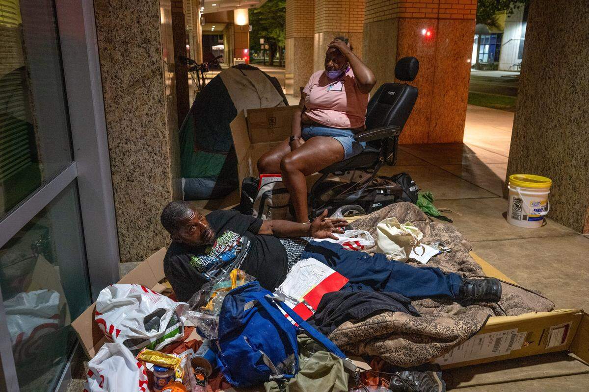 Under the lights of Sacramento City Hall, Gary Kelly, 68, and his partner of nine years, Xaveria Conley, 53, prepare to sleep on Tuesday, Aug. 19, 2025. Kelly suffers from multiple sclerosis and incontinence; Conley has cancer and injured knees. The couple said they have been sleeping outside City Hall for the past year, and were unaware that a new City Council ordinance will prohibit them from sleeping outside the building.