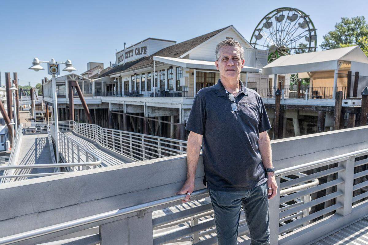 Rio City Cafe co-owner Jimmy Gayaldo stands in front of his Old Sacramento restaurant on Wednesday, June 12, 2024. The business, which rents the property from the city of Sacramento, has lost the use of its popular deck because of its landlord’s failure to make the required repairs.