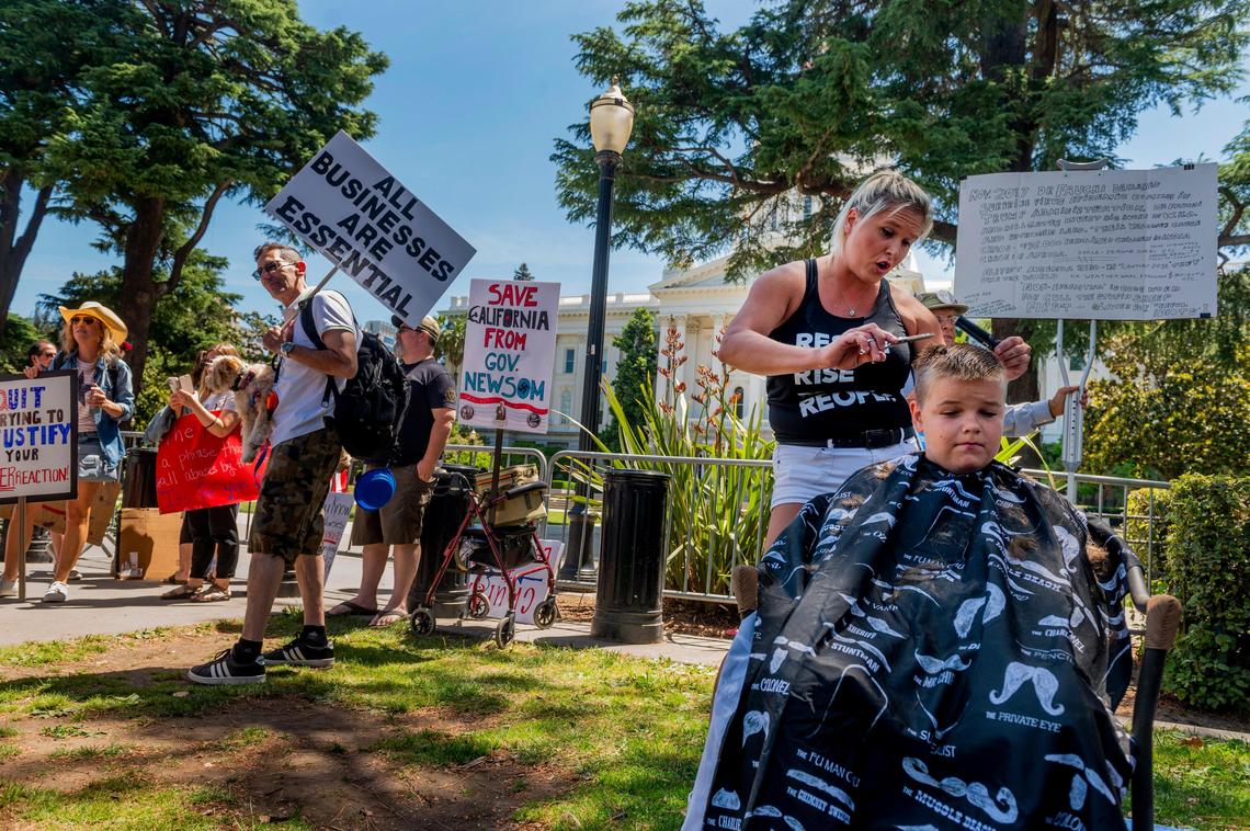 Hair stylist La Donna Christensen cuts Jordan’s hair in front of the west steps of the state Capitol on Saturday during Liberty Fest. At least 2,000 demonstrators protested near the Capitol on Saturday to call for California Gov. Gavin Newsom to lift coronavirus related restrictions.
