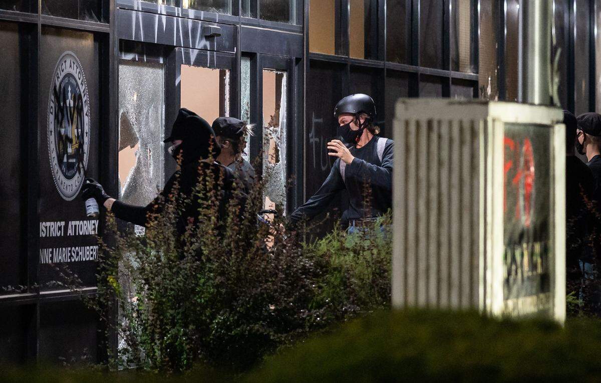 A man with a baseball bat smashes windows while others paint graffiti at the Sacramento County District Attorney’s Office in downtown Sacramento in a 2020 protest that followed the shooting of Jacob Blake, a 29-year-old Black man, in Kenosha, Wis.