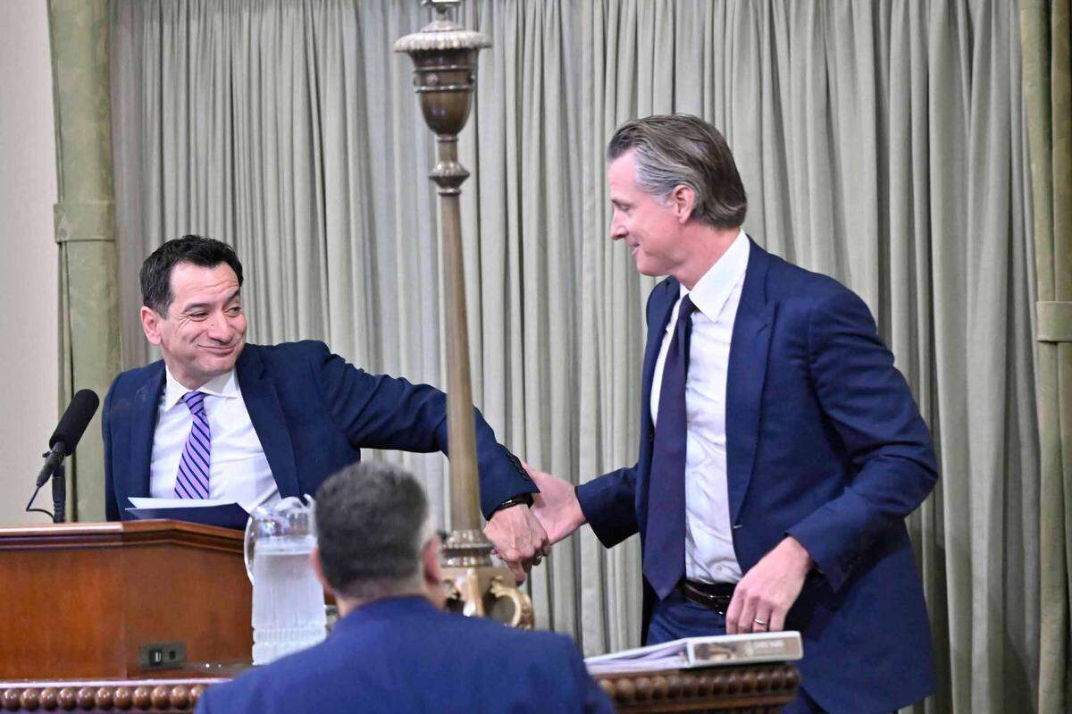 Gov. Gavin Newsom grabs the hand of departing speaker Lakewood Democrat Anthony Rendon while coming up to the podium at the swearing in ceremony for new Assembly Speaker Robert Rivas at the Capitol in Sacramento on Friday, June 30, 2023.