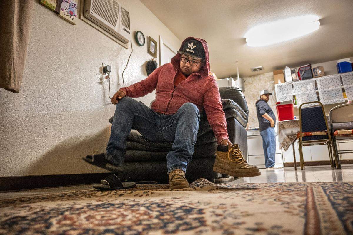 Carlos Alfonso Perez puts on his shoes at the Lodi Migrant Housing Center as he and his family prepare to go work in the fields in August.