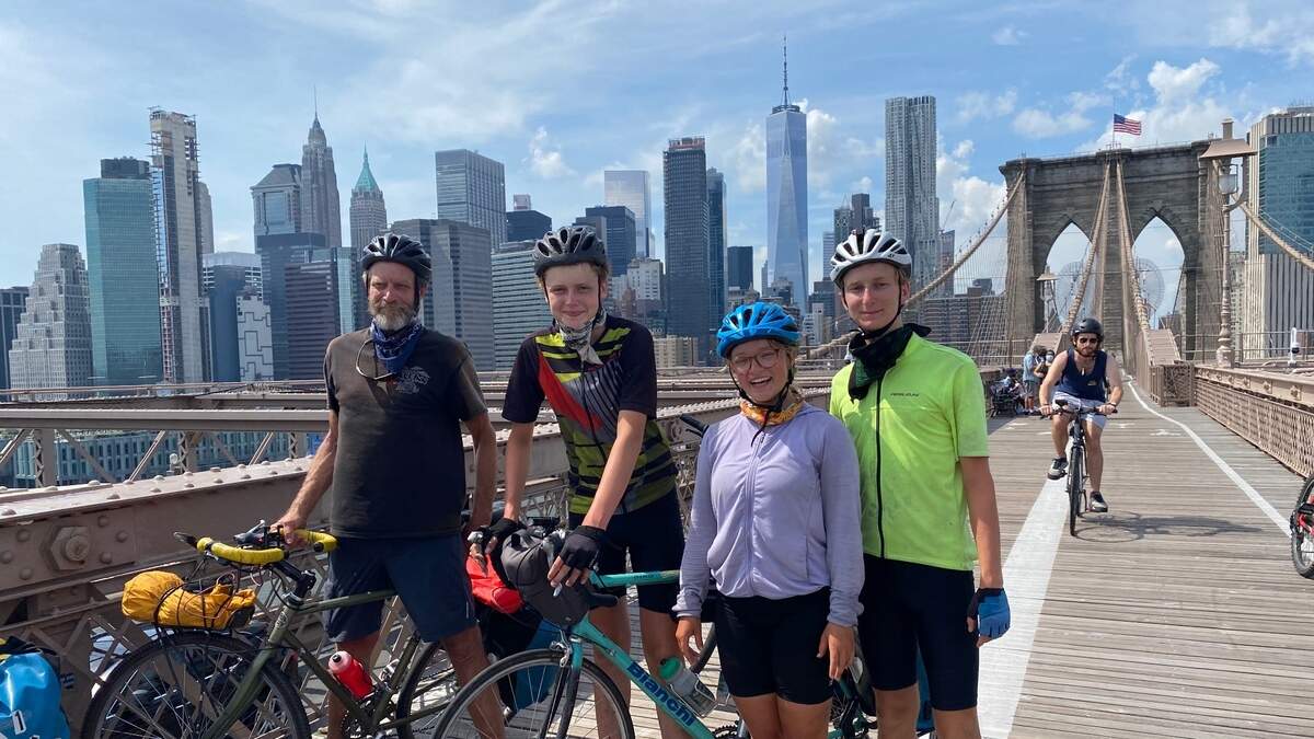 Three bikers and their teacher from California pose for a picture on the Brooklyn Bridge after a ride across the country.