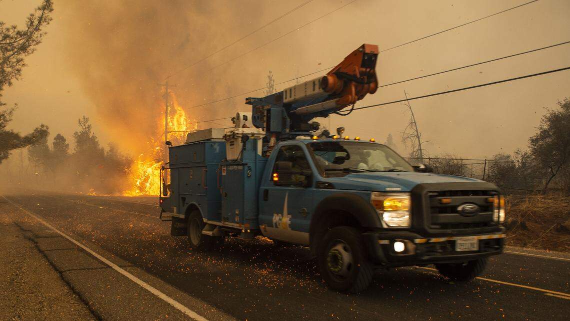A PG&E truck makes its way past a hot spot during the Camp Fire in Paradise in November. The utility is offering $105 million to help victims of the 2017 and 2018 fires, many of which have been blamed on PG&E.