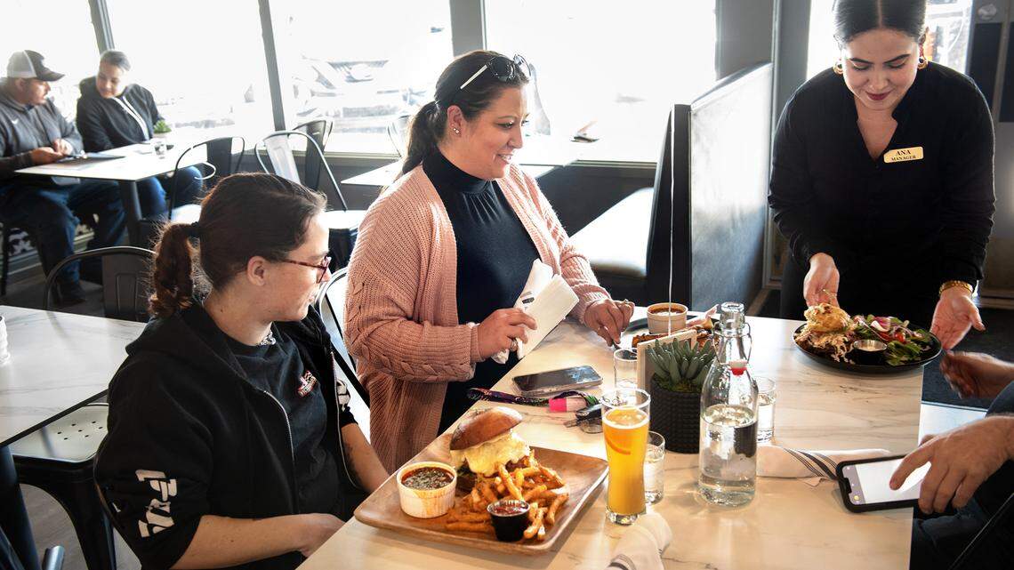 Manager Ana Espinosa, right, delivers lunch entrees to Jennifer Young, middle, and Miranda Dunn, left, at El Bistro by Salt and Pepper on Carpenter Road in Modesto, Calif., Thursday, April 13, 2023.