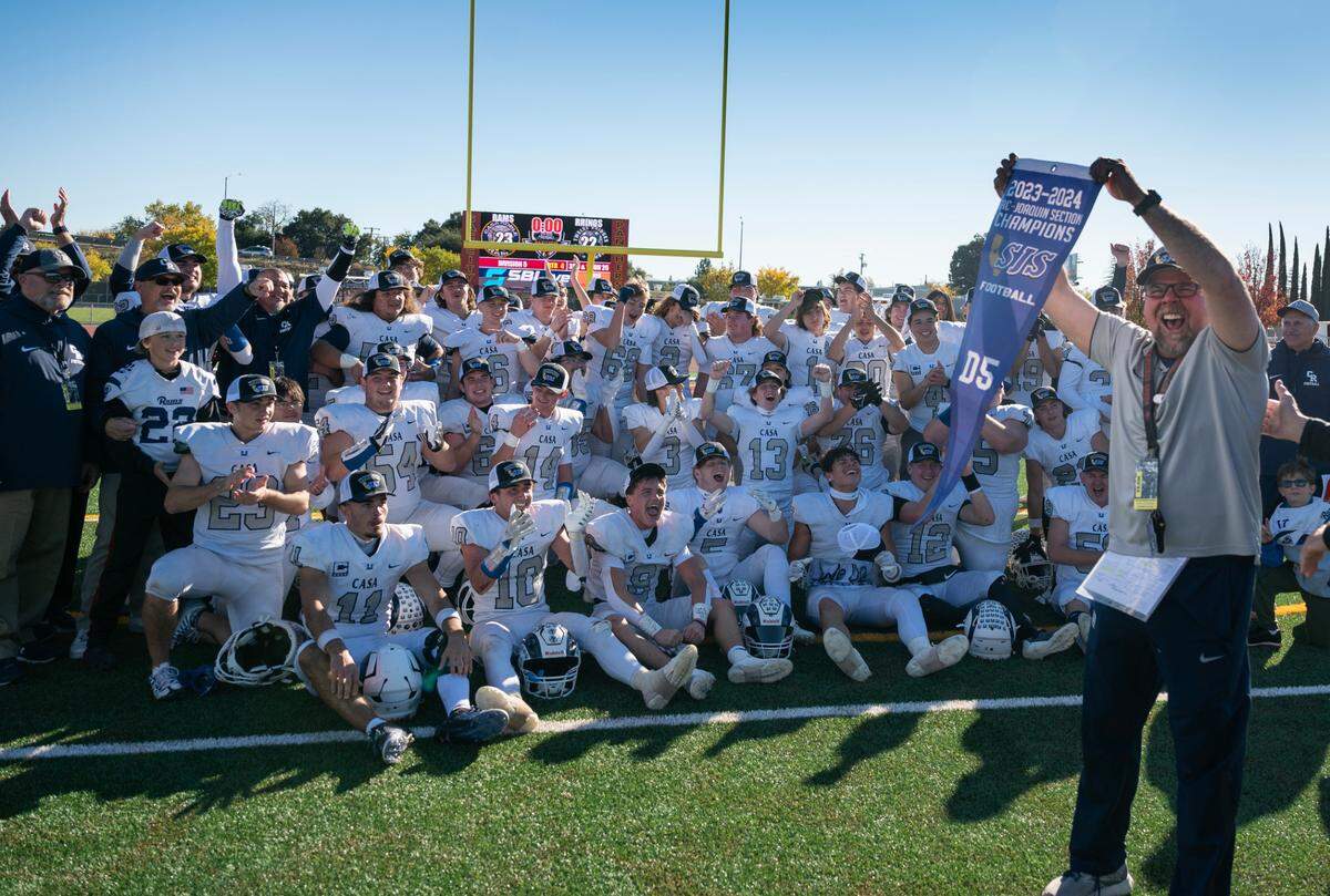 Casa Roble coach Chris Horner holds up the CIF Sac-Joaquin Section Division V championship banner after his team defeated top-seeded Twelve Bridges for the title on Friday at Hughes Stadium.