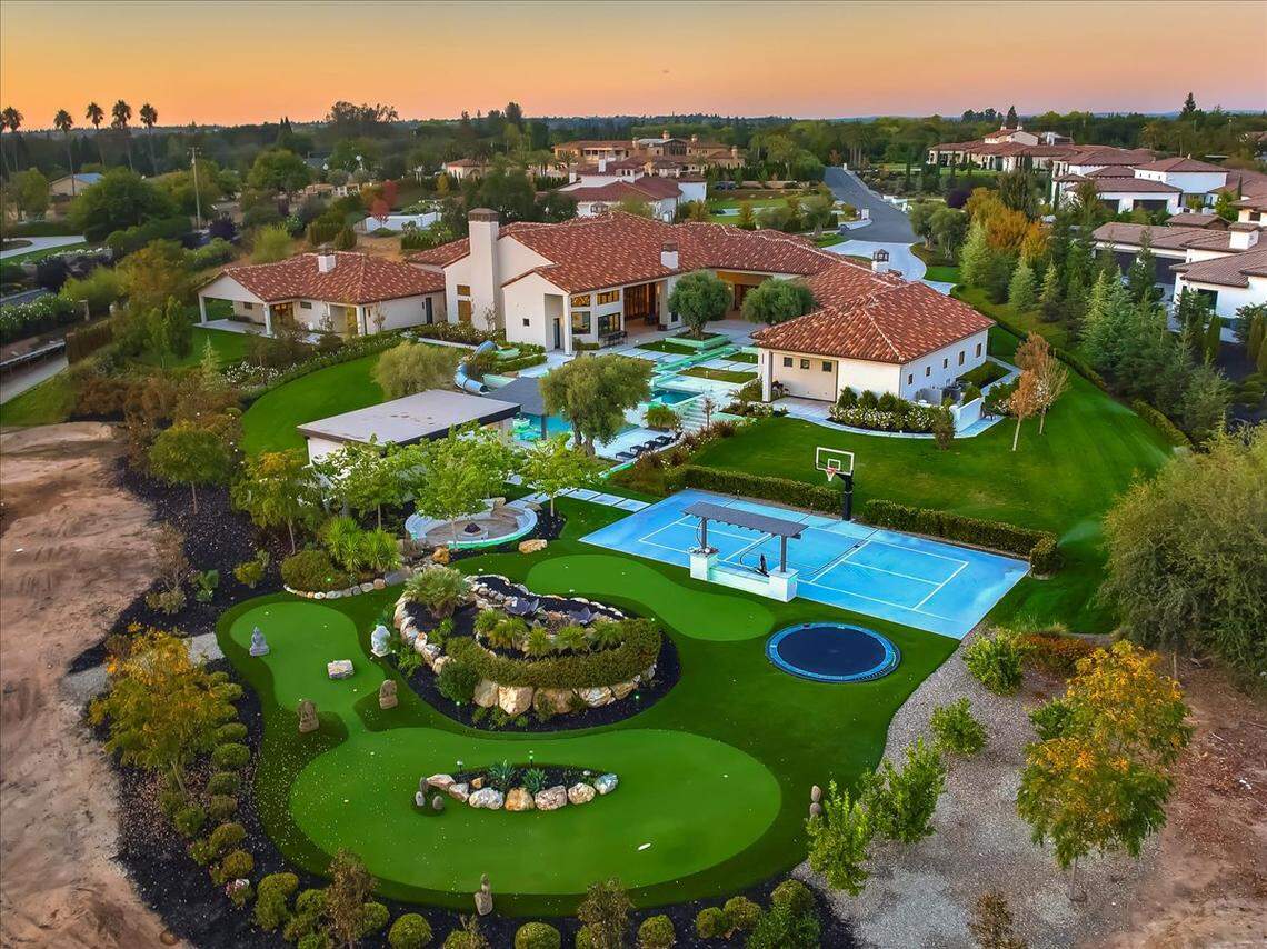 The backyard reads like a resort brochure that includes a putting course and sports court.