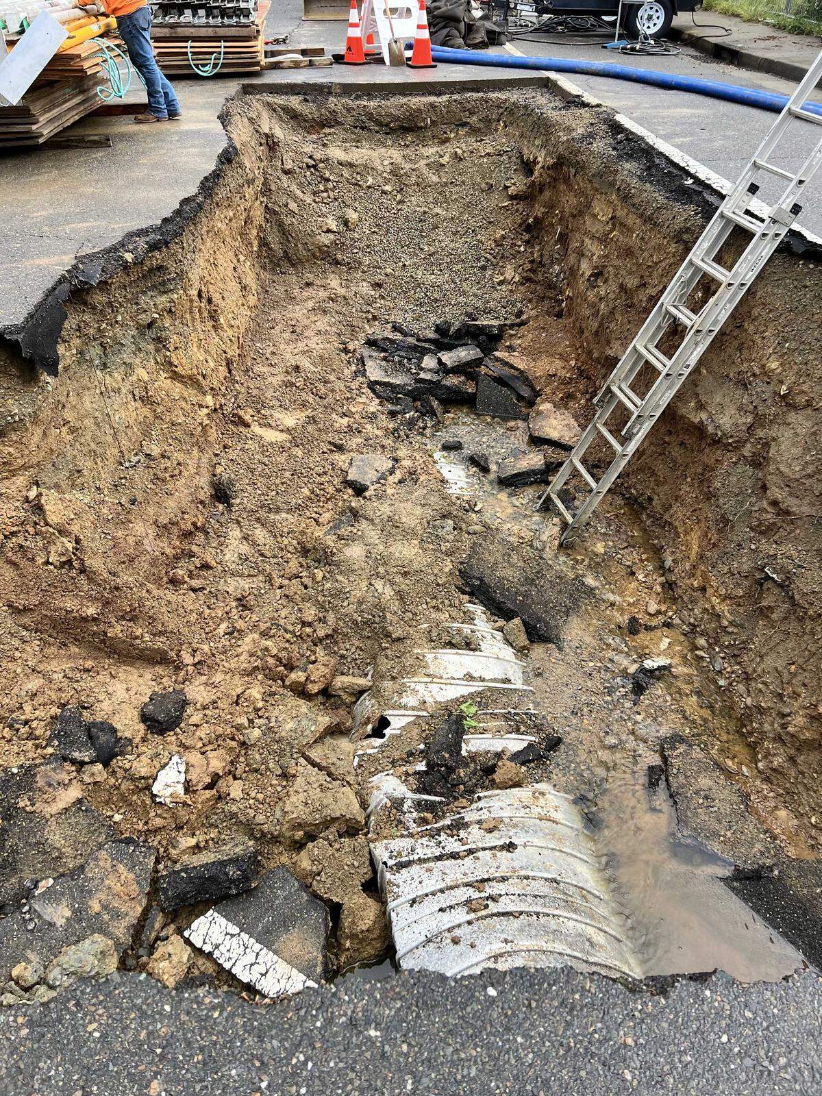 A large sinkhole blocks the intersection of Prewett and Newington drives in the Lexington Hills neighborhood of Folsom on Monday, April 13, 2026. The sinkhole opened after a series of weekend storms brought heavy rain to Northern California, prompting crews to install barriers and set up detours for residents.