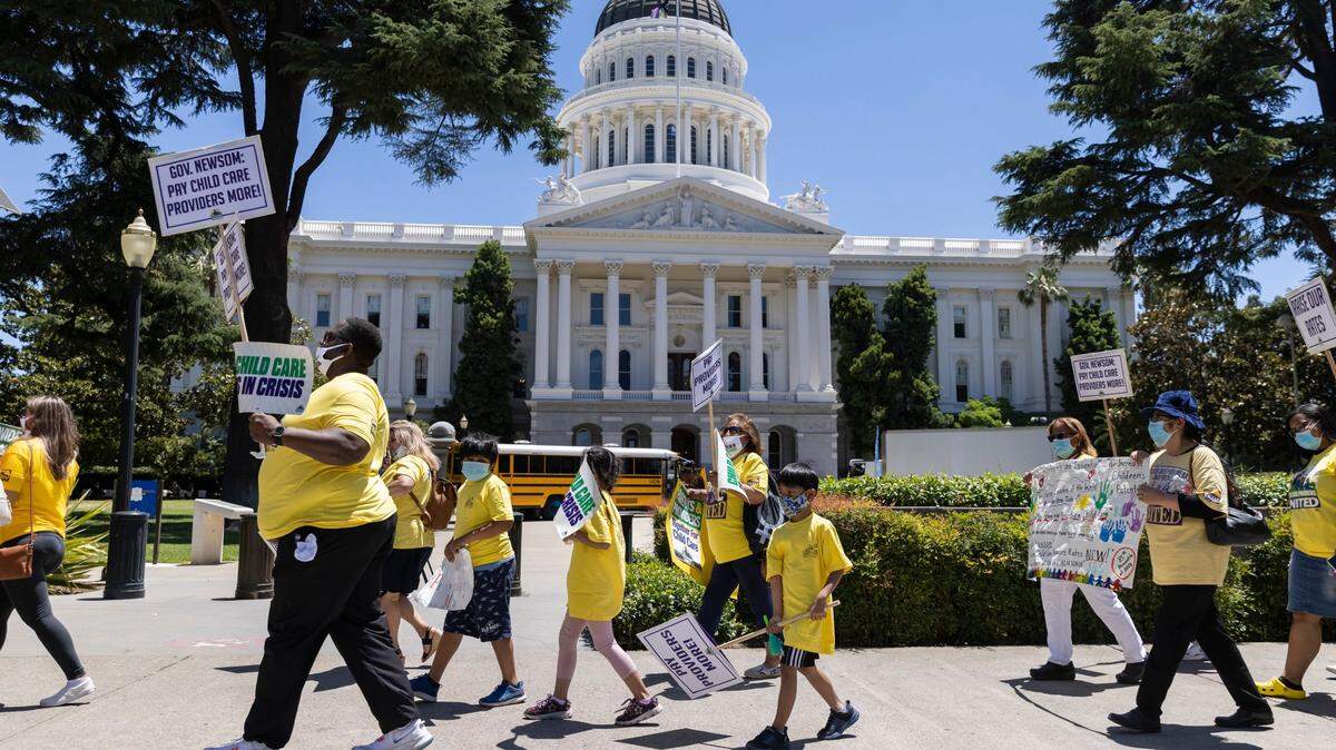 Members of Child Care Providers United, labor union formed in 2020 to represent California’s child care workers, and children march past the state Capitol in Sacramento on Tuesday, June 8, 2021, during a protest calling on Gov. Gavin Newsom to join them at the bargaining table to negotiate higher pay.