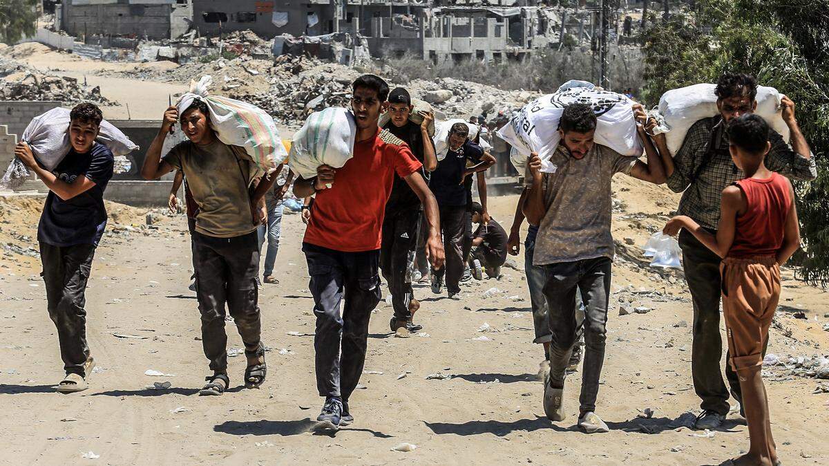 Palestinians carry sacks of flour after humanitarian aid supplies were airdropped by Qatari airplane over the Gaza Strip in July. 