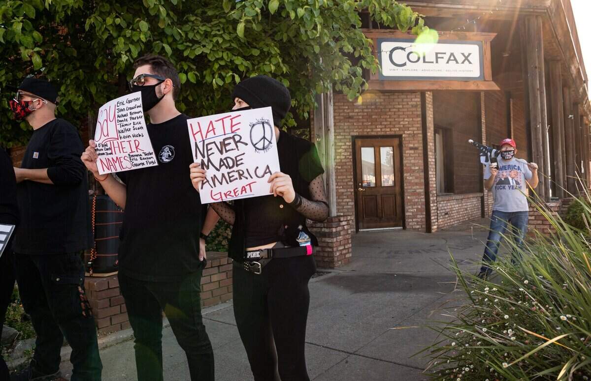Sequoia Rue, of Auburn protests against racism as Bill White, right, of the Auburn area, holds a version of the U.S. flag with a blue stripe while in Colfax on Wednesday.