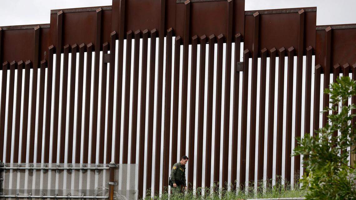 FILE - In this March 18, 2020, file photo, a Border Patrol agent walks along a border wall separating Tijuana, Mexico, from San Diego, in San Diego. Vice President Mike Pence in March directed the nation’s top disease control agency to use its emergency powers to effectively seal the U.S. borders, overruling the agency’s scientists who said there was no evidence the action would slow the coronavirus, according to two former health officials. (AP Photo/Gregory Bull, File)
