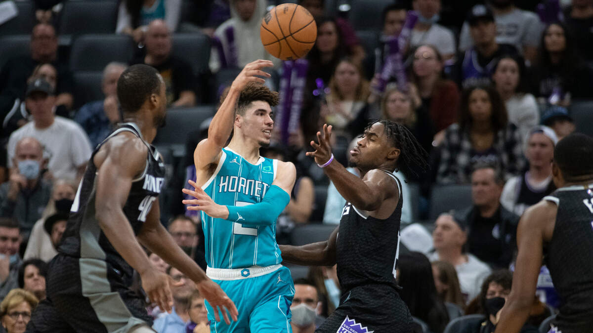 Charlotte Hornets guard LaMelo Ball (2) passes the ball over Sacramento Kings guard Davion Mitchell during the second half of an NBA basketball game in Sacramento, Calif., Friday, Nov. 5, 2021. The Kings won 140-110. (AP Photo/Randall Benton)