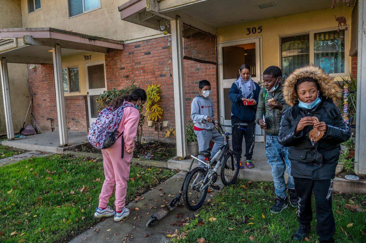Jasmine Singh, center, hands out fresh chocolate chip cookies to neighboring children Vonte Stephens, 11, and Javaughn Eiland, 12, right, as her grandchildren Justin Carter, 13, and Niyah Carter, 12, left, return home from school on Dec 14. Singh worries about the future of the children in the Sacramento public housing development and says there’s few resources for the “kids to just be kids outdoors.”