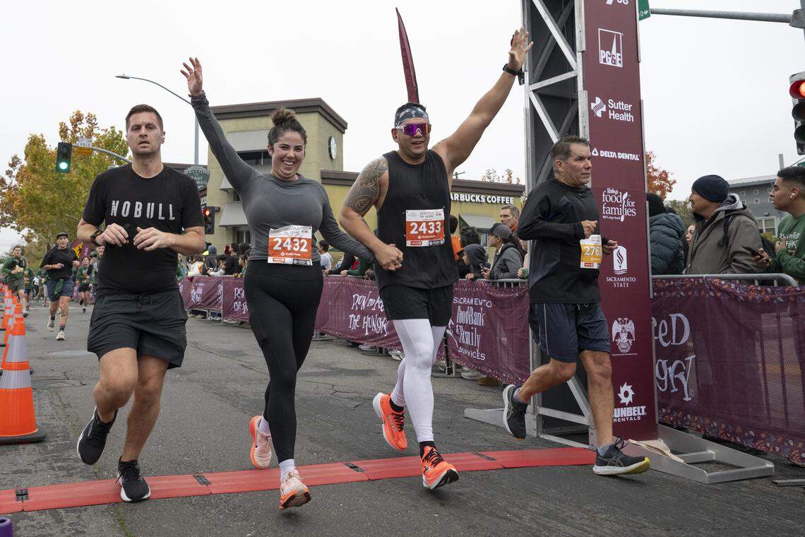 Runners cross the finish line of the 10k race during the Run to Feed the Hungry in Sacramento on Thursday, Nov. 27, 2025.