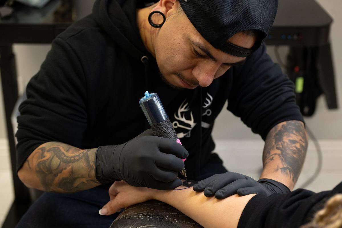 Tattoo shop owner Edgar Avila touches up a tattoo by another tattoo artist for customer Sarah Duplantier at Elk Grove Tattoo on Friday, Dec. 8, 2023.