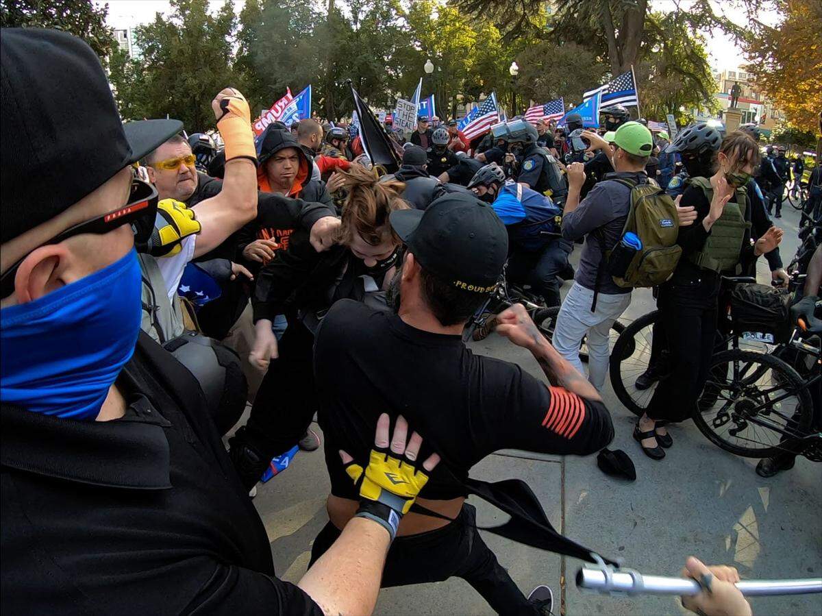 Members of the Proud Boys brawl with counter-protesters at Cesar Chavez Plaza in Sacramento after a Trump rally was held near the Capitol on Saturday, Nov. 21, 2020. Local law enforcement tried to keep the two groups separated with barricades as they rallied near the Capitol but the Trump group managed to break through and marched to Cesar Chavez Plaza where they were confronted by counter protesters, leading to a large fight. Sacramento Police officers declared an unlawful assembly and dispersed both sides from the park.
