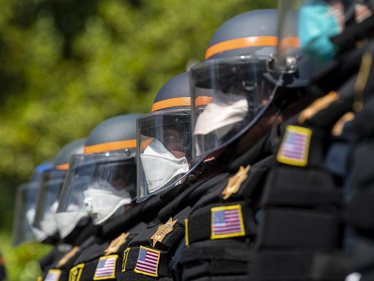 California Highway Patrol officers wearing face masks under their tactical helmets prepare move protesters back at a demonstration at the Capitol in Sacramento on Friday, May 1, 2020, against Gov. Gavin Newsom’s stay-at-home order to slow the spread of the coronavirus.