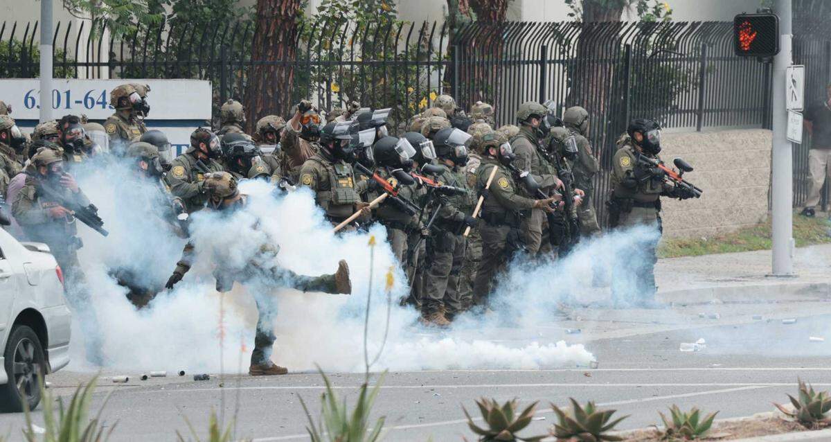 Federal law enforcement officers kick tear gas back to the crowd as people block off the street and set a fire during protests against ICE and immigration raids on Saturday, June 7, 2025, in Paramount. Gov. Gavin Newsom condemned the announced federal deployment of National Guard troops to the area Saturday, calling it “purposefully inflammatory” and warning it would “erode public trust.”