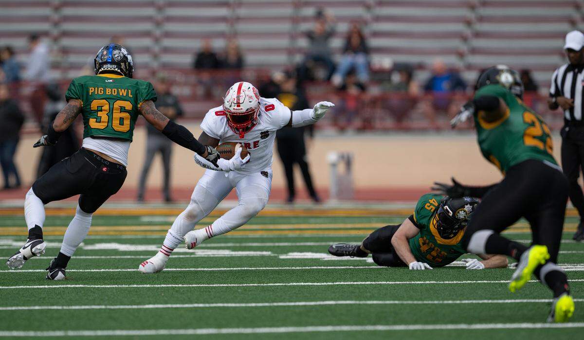 Fire Dogs running back Komi Tay rushes for a short gain against the Law Hogs in the 50th Pig Bowl on Saturday at Hughes Stadium.