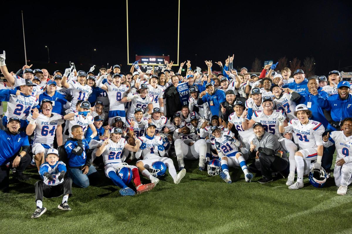 Folsom Bulldogs pose with the section title banner after the Sac-Joaquin Section Division I championship game at Hughes Stadium in Sacramento on Friday. The Bulldogs won 20-3.