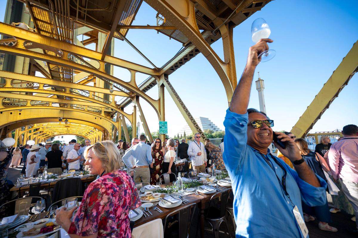 Guneet Bajwa of Presidio Companies, owner of Hyatt hotels including the Hyatt Centric Downtown Sacramento, holds up his glass while trying to find a guests at the Farm-to-Fork Festival’s Tower Bridge Dinner on Sunday.