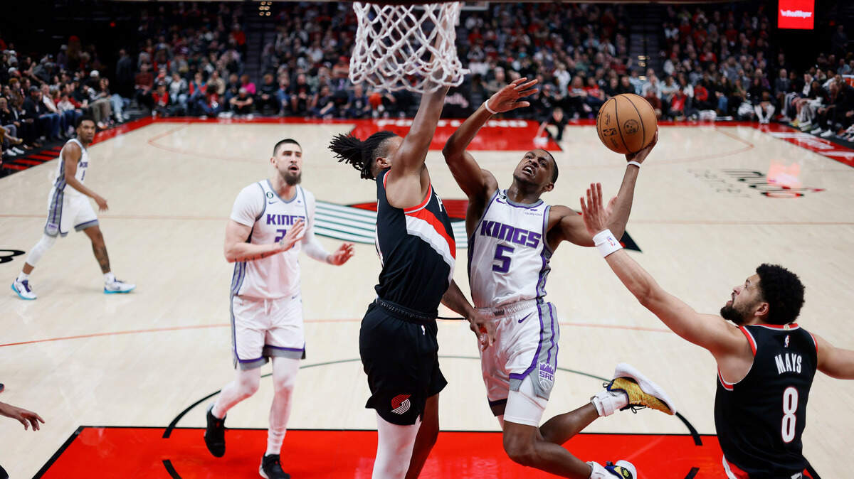 Sacramento Kings point guard De’Aaron Fox (5) shoots under pressure from Portland Trail Blazers forward Jabari Walker during the first half on Friday, March 31, 2023 at Moda Center in Portland, Ore.