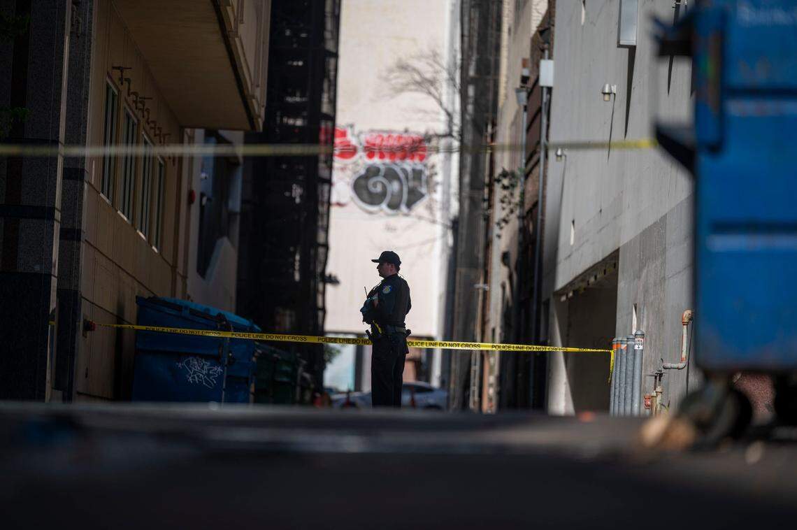 A Sacramento Police officer stands guard on J Street near an alley after an early morning shooting that killed six and wounded 12 people in downtown Sacramento on Sunday, April 3, 2022.