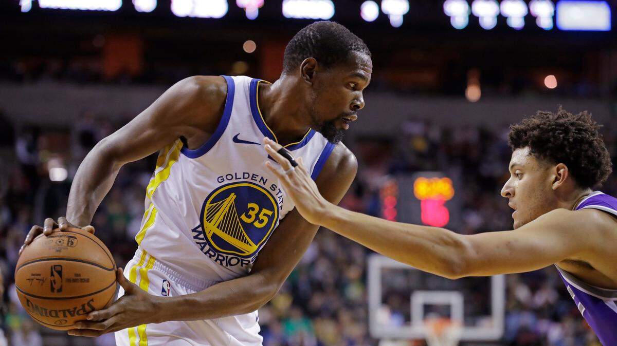 Golden State Warriors forward Kevin Durant, left, looks to pass the ball as Sacramento Kings forward Justin Jackson defends during the first half of an NBA basketball preseason game Friday, Oct. 5, 2018, in Seattle.