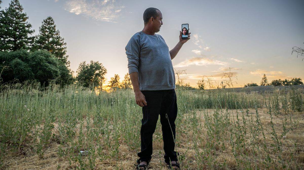 Diego de Jesús Delgado Meléndez, one of 36 migrants flown to Sacramento by Florida Gov. Ron DeSantis in June, talks to his wife in Colombia on his cell phone Wednesday. The couple from Venezuela are looking to save $5,000 to buy a home there.