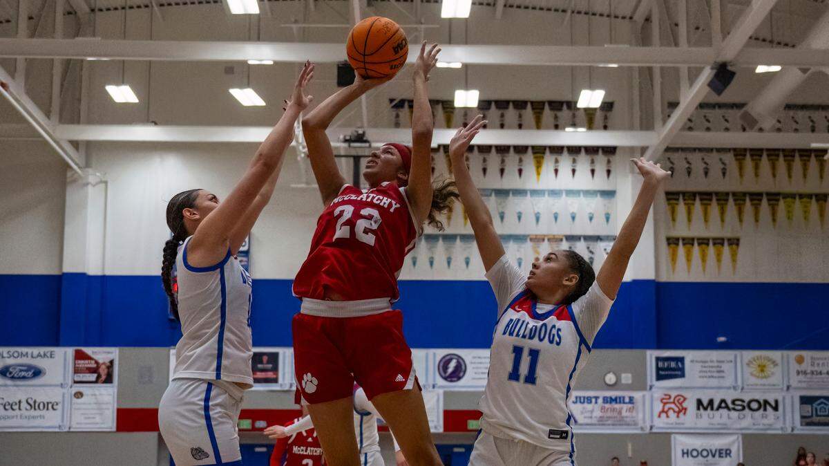 The McClatchy Lions’ Nina Cain (22) takes a jump shot while defended by the Folsom Bulldogs’ Kamryn Mafua, left, and Aryn Bright (11) in the second quarter of a CIF Sac-Joaquin Section girls basketball semifinal on Monday, Feb. 19, 2024, in Folsom.