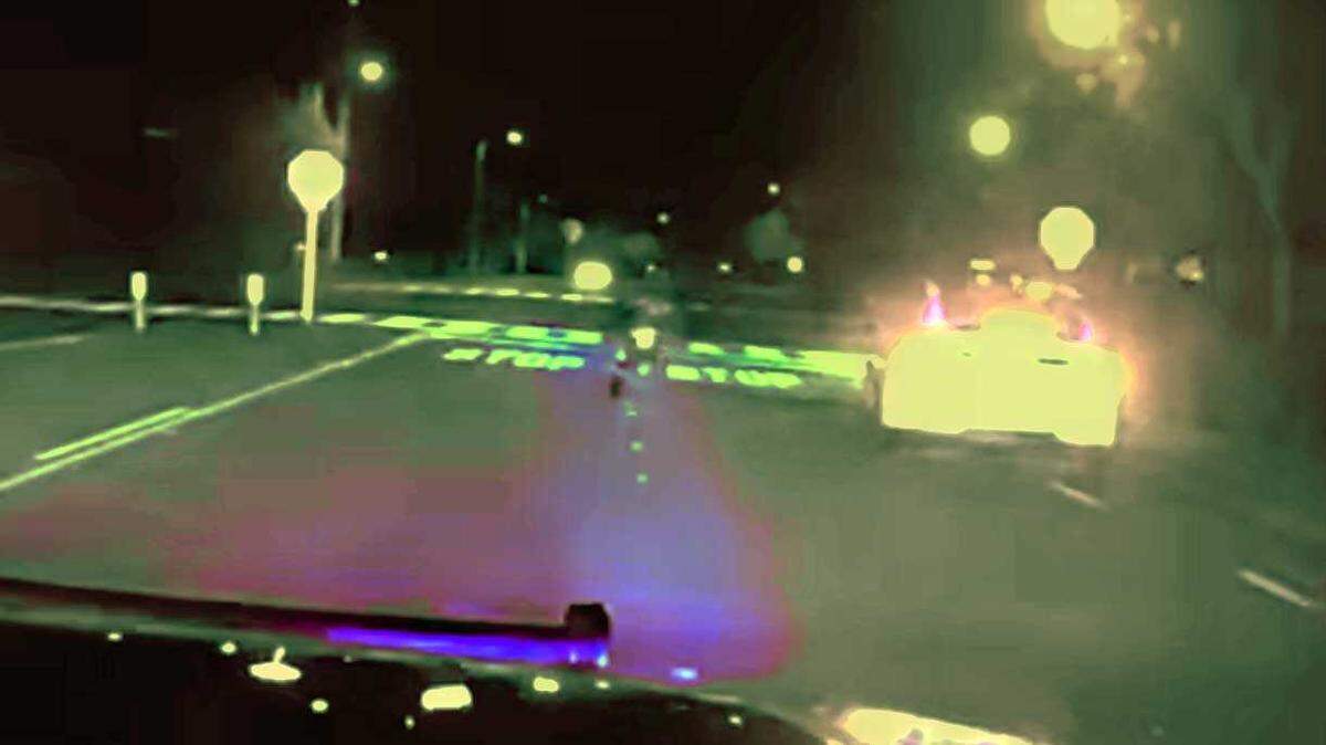 A teen on an e-bike, center, is seen riding on the striped lines next to a vehicle as a police officer chases him in Folsom on Sunday, Dec. 30, 2024.