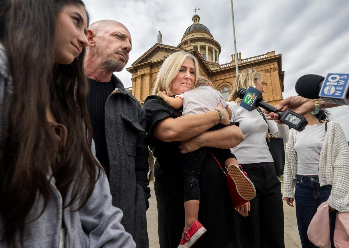Elizabeth Dillender, center, hugs her two-year-old granddaughter Indigo Kade Webb while speaking to the media on Sept. 17 after the murder conviction of Carson David Schewe in Placer Superior Court in Auburn. Schewe sold fentanyl-laced pills to Kade Kristopher Webb, Dillender’s son and Indigo’s father. Kurt Webb, Kade’s father, stands at left.