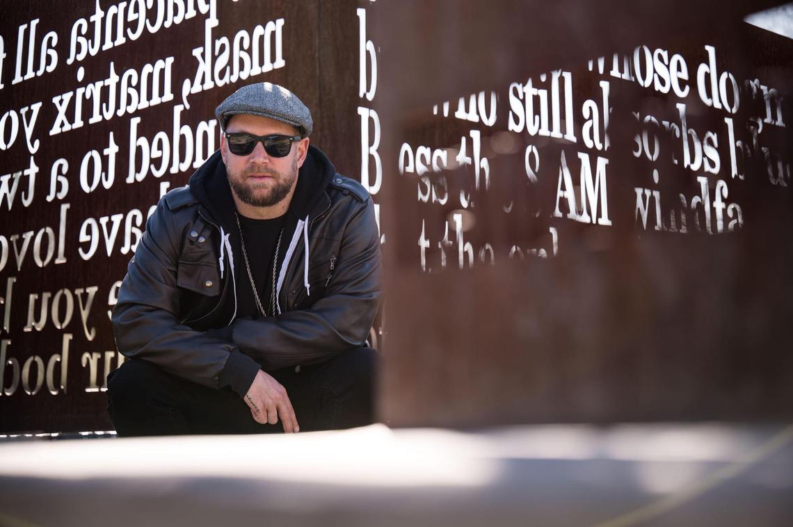 Andrew Bell, known as the the Sacramento Poet Laureate Andru Defeye, is photographed amid the words of previous Sacramento poets laureate in regional artist Troy Corliss’ “Poet’s Path, Circle of Laureates” art installation Wednesday, March 15, 2023, at South Natomas Community Park.