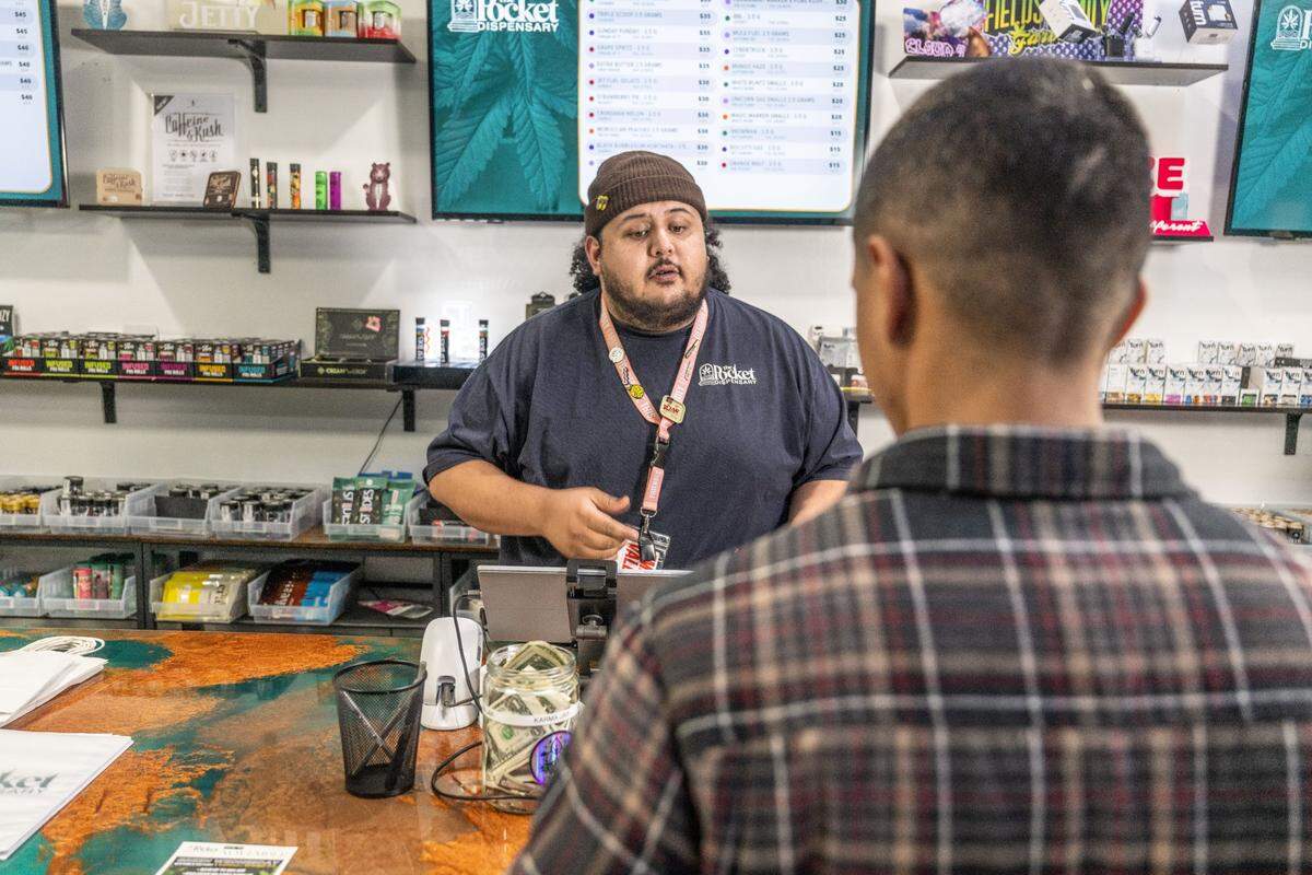 Tony Mendez, a bud tender at The Pocket Dispensary in Sacramento, helps a client with a purchase last month.