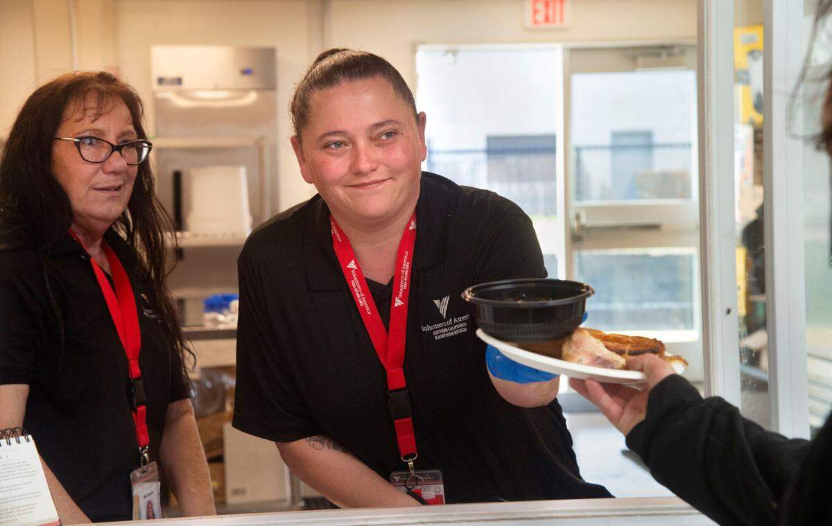 Volunteers of America staff members Michele Mello, left, and Jenna Winn serve lunch guests at the VOA’s X-Street Navigation Center on Wednesday, Dec. 1, in Sacramento.