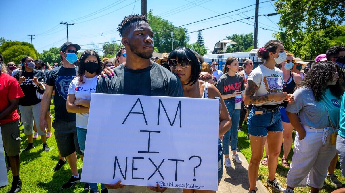 Adreena Island, 49, of Vacaville, rests her head on the shoulder of her son, Christopher Island, 17, as he holds a sign that says “Am I next?” on Wednesday at Shiloh Baptist Church in Oak Park during a protest over the death of George Floyd, a black man who died after being restrained by Minneapolis police officers on May 25.
