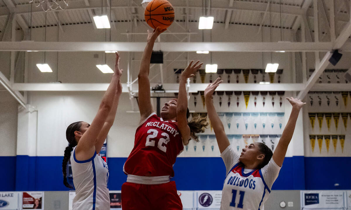 The McClatchy Lions’ Nina Cain (22) takes a jump shot while defended by the Folsom Bulldogs’ Kamryn Mafua, left, and Aryn Bright (11) in the second quarter of a CIF Sac-Joaquin Section girls basketball semifinal on Monday.