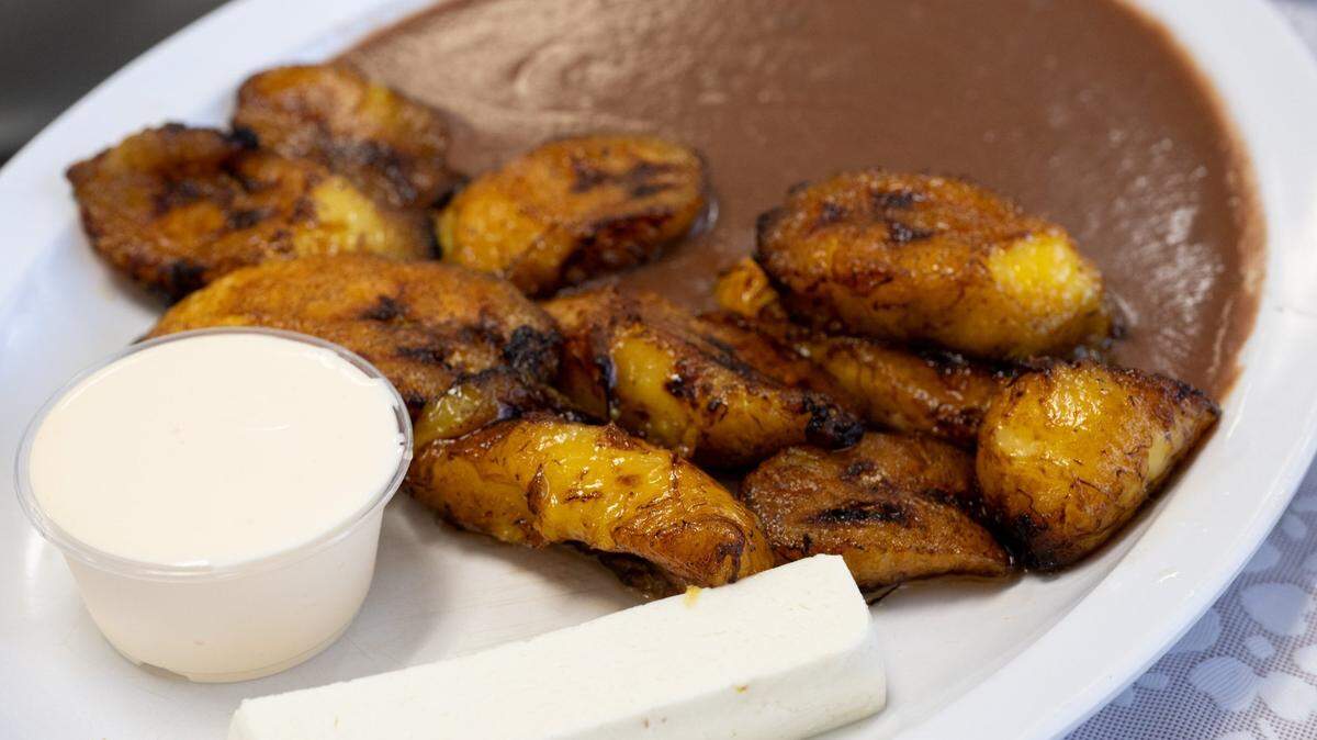 A plate of platano ($4.99), or fried plantains, is served with a side of beans, Salvadorian sour cream and a piece of fresh cheese at Pupusas Central in Sacramento on Thursday, May 8, 2025.