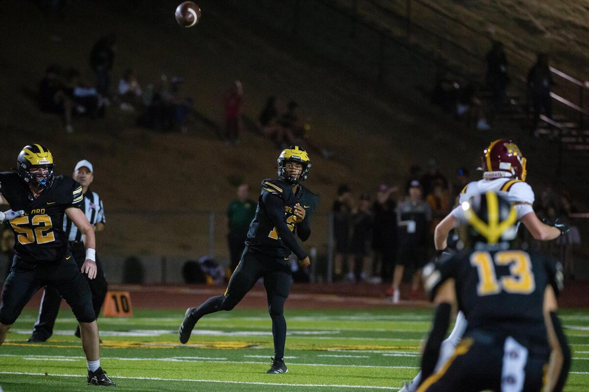 Del Oro quarterback Caden Pinnick (12) throws the ball to Tommy Poe (13) for a first down during the second quarter in the game Friday, Sept. 16, 2022, at Del Oro High School in Loomis.