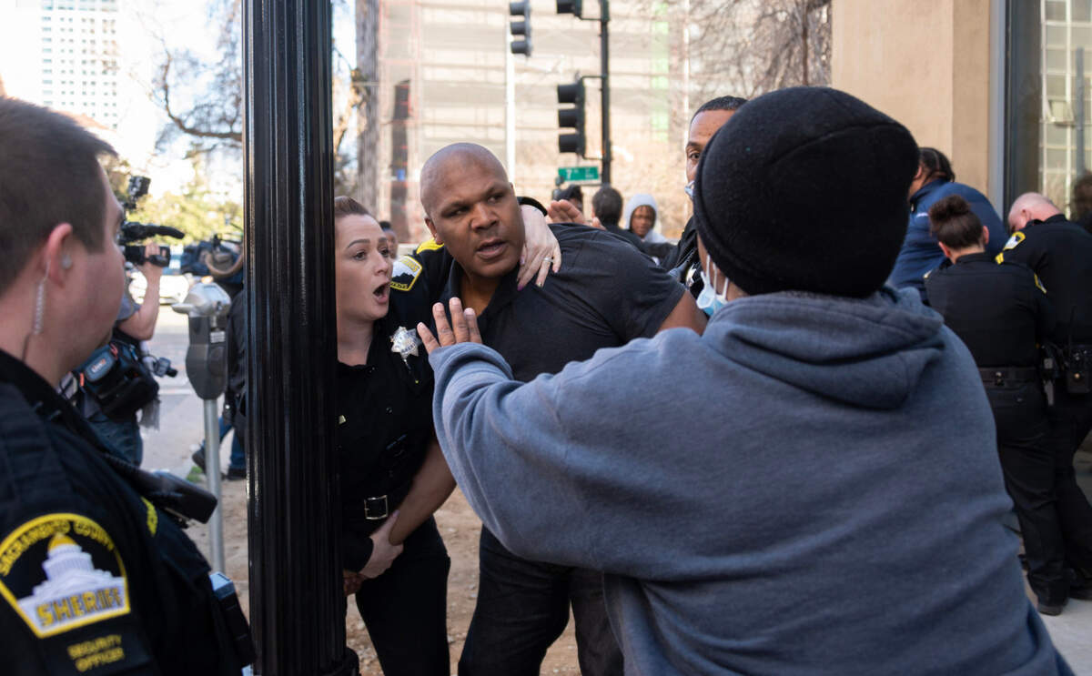 A Sacramento Sheriff’s deputy restrains a family member who participated in the scuffle between the families of the defendant and the victims after the arraignment of Cameron Garcia, who is accused of killing five people in a crash on Highway 160 near Freeport Bridge, outside of the Sacramento Main Jail following Garcia’s arraignment in Superior Court on Tuesday.